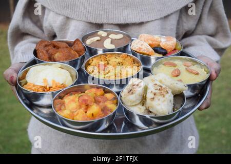 Piatti tradizionali indiani Farali serviti in thali e bocce con molti oggetti per upawas upawas o vrat ka khana. Decorato con petali di fiori per il digiuno Foto Stock