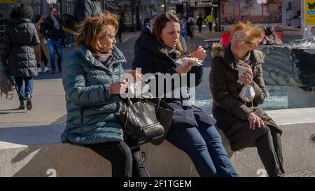 Le Signore con le maschere si incontrano per godersi un panino da asporto e il sole primaverile nel centro turistico di Baden-Baden durante la chiusura dei ristoranti. Foto Stock