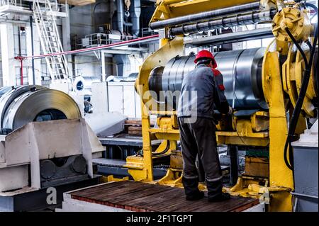 Operai di fabbrica che imballano i rotoli di lamiera d'acciaio in impianti industriali. Produzione di hardware Foto Stock