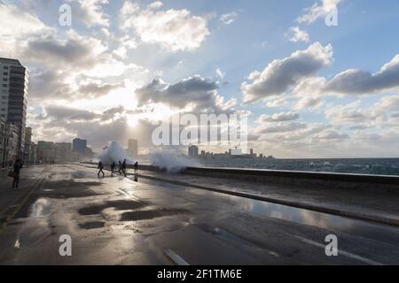 Cuba, l'Avana - la gente sul Malecon in un giorno di tempesta bagnata mentre le onde si schiantano sul Malecon Foto Stock