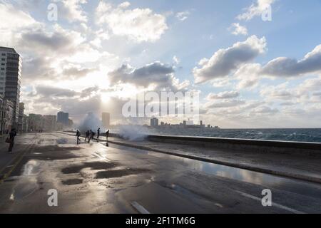 Cuba, l'Avana - la gente sul Malecon in un giorno di tempesta bagnata mentre le onde si schiantano sul Malecon Foto Stock