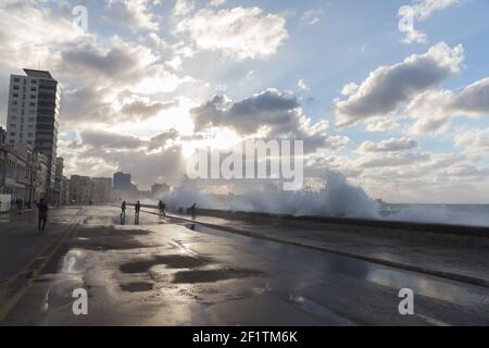 Cuba, l'Avana - la gente sul Malecon in un giorno di tempesta bagnata mentre le onde si schiantano sul Malecon Foto Stock