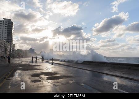 Cuba, l'Avana - la gente sul Malecon in un giorno di tempesta bagnata mentre le onde si schiantano sul Malecon Foto Stock