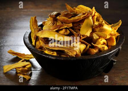 mango organico essiccato in una ciotola di legno su sfondo di legno Foto Stock