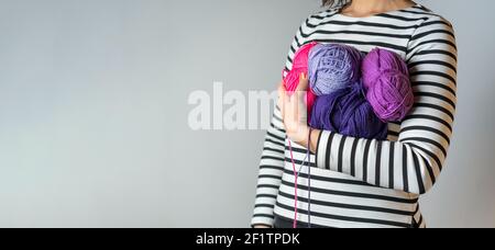 Donna con T-shirt a righe e smalto arancione il suo braccio alcune palline colorate di lana acrilica con copia spazio Foto Stock