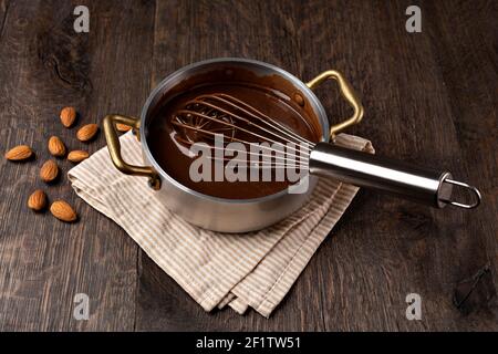 Crema di cioccolato liquido che si versa da una frusta in un mestolo. Foto Stock