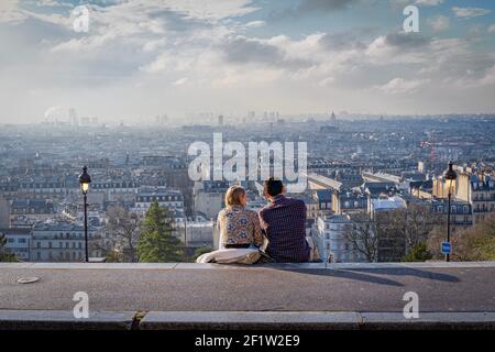 Parigi, Francia - 02 26 2021: Quartiere di Montmartre. Vista di Parigi da piazza Louise Michel e una giovane coppia seduto sui gradini Foto Stock