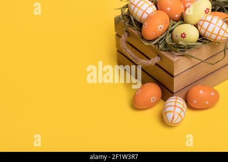 Uova colorate di Pasqua in un cestino isolato su uno sfondo giallo illuminante alla moda. Concetto di pasqua minimo. Carta di Pasqua con spazio per la copia del testo. Foto Stock