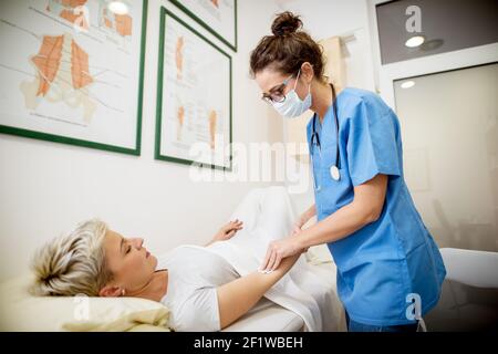 Primo piano della vista verticale dell'infermiere professionista di mezza età che tiene le mani con un paziente mentre la paziente è distesa sul letto davanti. Foto Stock