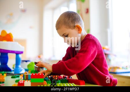 Il ragazzo prescolare immerso in un gioco con un costruttore Foto Stock