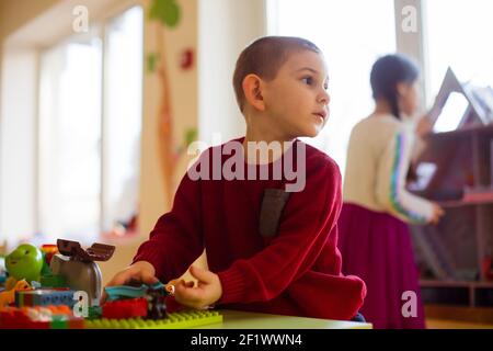 Il ragazzo prescolare immerso in un gioco con un costruttore Foto Stock