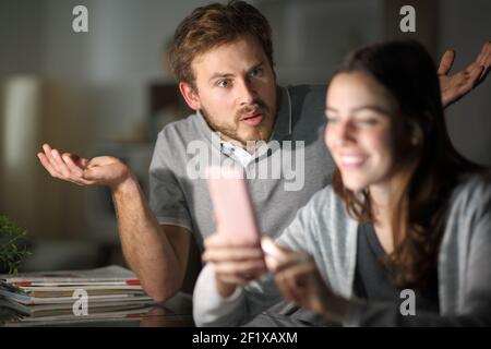 Moglie che usa lo smartphone sta ignorando suo marito in notte a casa Foto Stock