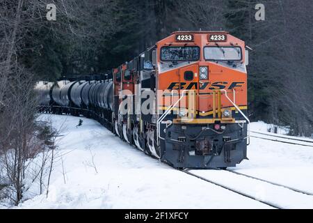 Treno ad olio BNSF in direzione est presso Skykomish nello stato di Washington con neve a terra Foto Stock