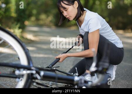 donna che pompa su un pneumatico della bici Foto Stock