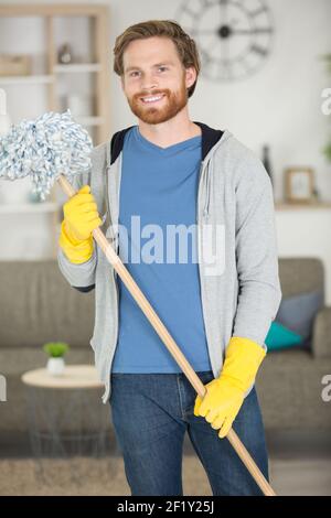 ritratto di giovane uomo che tiene un mop pavimento Foto Stock