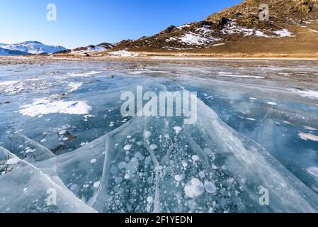 Vista della bella disegni su ghiaccio da crepe e bolle di gas in profondità sulla superficie del lago Baikal in inverno, Russia Foto Stock