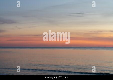 Un bellissimo tramonto sull'oceano con il cielo colorato e. onde piccole Foto Stock
