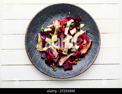 Insalata con aringhe, barbabietole, cipolle e piselli verdi. Insalata di filetto di aringa salato Foto Stock