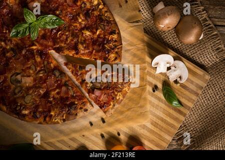 Pizza italiana appena sfornata con ingredienti su legno rustico antico tabella Foto Stock