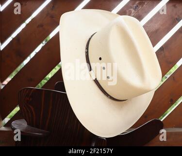 Cappello di cowboy bianco peso su una piccola sedia basculante. Foto Stock