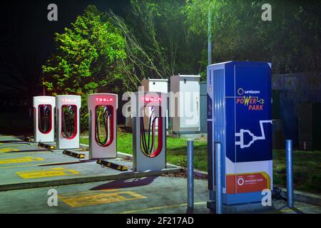 Una fila di stazioni di ricarica per veicoli elettrici di notte. La maggior parte di loro ha il logo Tesla. Taupo, Nuova Zelanda Foto Stock