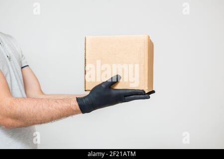 Mani dei corrieri in guanti di gomma medica e maschera protettiva che contiene scatole di cartone. Consegna porta. Cibo da asporto. Servizio di consegna. Quarantena. Coron Foto Stock