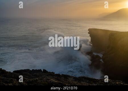 Una vista di enorme tempesta che si infrangono le onde oceaniche riva e scogliere all'alba Foto Stock