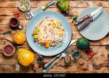 Tradizionale piatto italiano spaghetti carbonara con zucca e pancetta.Pasta carbonara.Pasta con zucca al forno Foto Stock