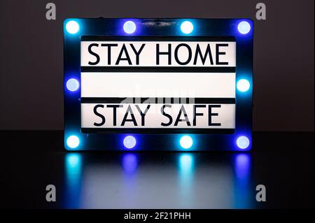 Scatola luminosa con luci verdi e blu in camera oscura con le parole "Say home, Stay safe" Foto Stock