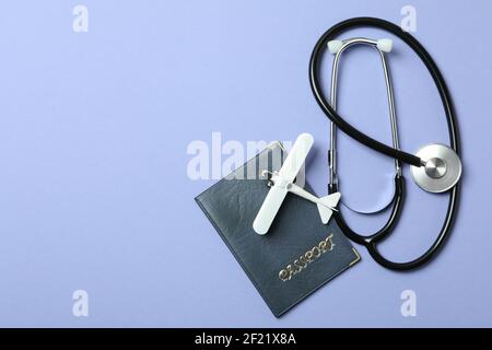 Passaporto, stetoscopio e piano giocattolo su sfondo viola Foto