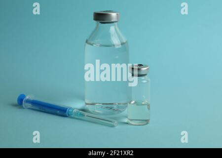 Fiale con vaccino COVID-19 e una siringa su sfondo blu, concetto di immunizzazione visto dall'alto Foto Stock