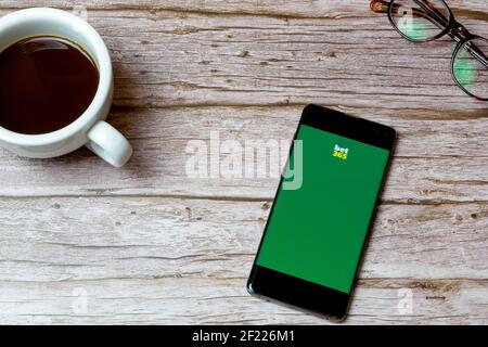 Un telefono cellulare o un telefono cellulare posto su un tavolo O scrivania con l'app Bet 365 aperta e una caffè accanto ad esso Foto Stock