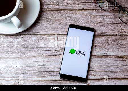 Un telefono cellulare o un telefono cellulare posato su un legno Tavolo con l'app Hello Fresh aperta accanto a caffè e bicchieri Foto Stock
