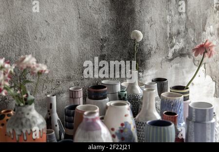 Bouquet di fiori in assortiti fatti a mano molti vasi in ceramica diversi con vecchia parete di cemento. Arredamento domestico. Messa a fuoco selettiva. Foto Stock