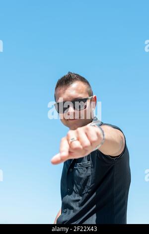 Uomo felice che punta le dita verso la telecamera sullo sfondo del cielo. Foto Stock