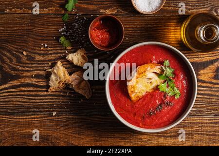 Ciotola di zuppa di pomodoro con pane tostato su legno rustico sfondo direttamente sopra Foto Stock