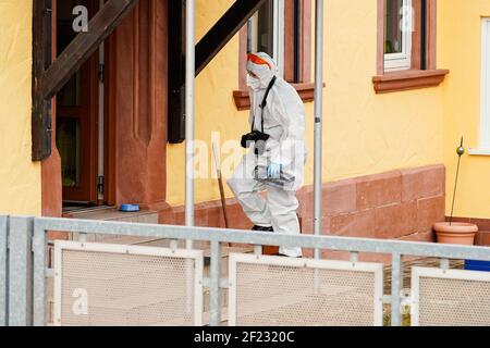 Weilerbach, Germania. 10 marzo 2021. Un dipendente del dipartimento di medicina legale entra in una casa residenziale in una proprietà all'ingresso del villaggio. Dopo la scoperta di due corpi in una casa a Weilerbach vicino Kaiserslautern, la polizia continua a cercare un sospetto a piena velocità. Credit: Uwe Anspach/dpa/Alamy Live News Foto Stock