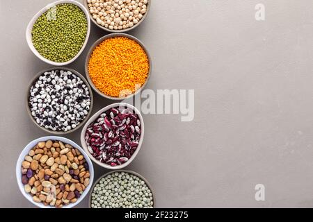 Diversi tipi di legumi in ciotole, piselli verdi e gialli, ceci e arachidi, fagioli e lenticchie colorate, fagioli e fagioli, vista dall'alto Foto Stock