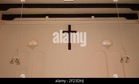 Muro dietro l'altare: Croce appesa al muro, luci appese e travi orizzontali in legno sulla parete della Chiesa di Cristo a Malacca (Melaka) Malesia Foto Stock
