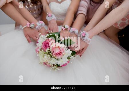 Un closeup di mani di sposa e bridesmaids con bouquet e braccialetto fiore Foto Stock