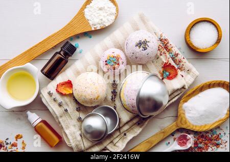 Fare bagno fizz bombe a casa concetto. Tutti gli ingredienti sul tavolo su cucchiai di legno: Amido di mais, olio essenziale, colorante, acido citrico, bicarbonato di sodio. Foto Stock