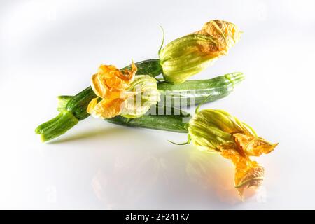 Zucchine con fiori su fondo bianco. Verdure di stagione concetto. Foto Stock