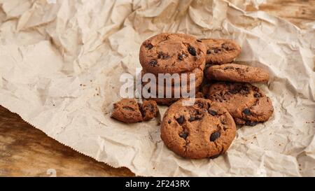 Vista su alcuni biscotti fatti a mano al cioccolato con scaglie di cioccolato sulla cottura carta Foto Stock