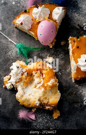 Vista ad alto angolo di alcuni pezzi di una mona de pascua spagnola, una torta mangiata il lunedì di Pasqua, decorata con un uovo ornato e piume di diverso Foto Stock
