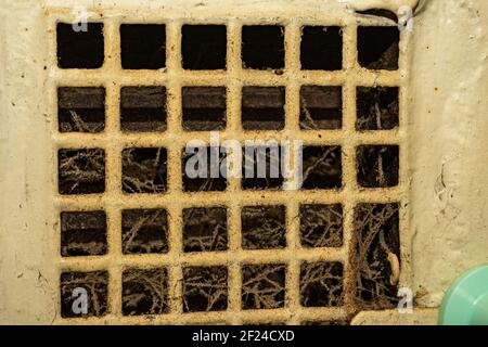 Una vecchia griglia di ventilazione, ostruita da ciottoli e muffa. Impianto di ventilazione intasato e sporco. Foto Stock