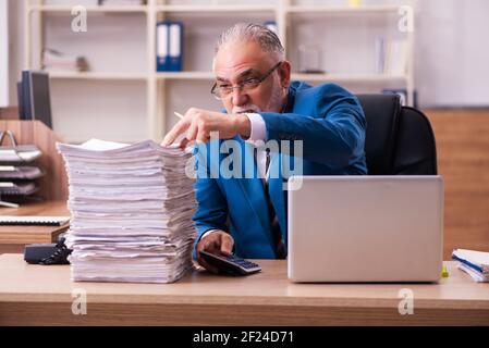 Il vecchio dipendente maschio è insoddisfatto del lavoro eccessivo in ufficio Foto Stock