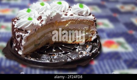 pan di spagna panna a strati, tagli a metà. Piano con panna montata e decorazioni di frutta candita verde. Su vassoio di plastica della confezione. Con percorso di ritaglio Foto Stock