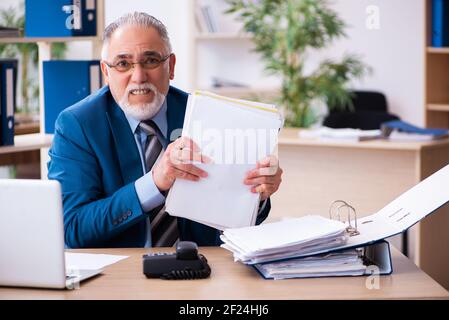 Il vecchio contabile maschile è infelice del lavoro eccessivo sul posto di lavoro Foto Stock