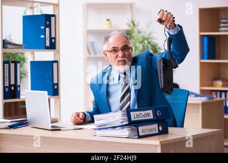 Il vecchio contabile maschile è infelice del lavoro eccessivo sul posto di lavoro Foto Stock