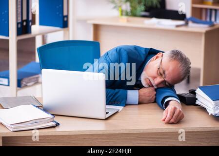 Il vecchio contabile maschile è infelice del lavoro eccessivo sul posto di lavoro Foto Stock